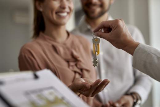 Vermieten Nahaufnahme eines Immobilienmaklers, der einem Paar neue Hausschlüssel gibt